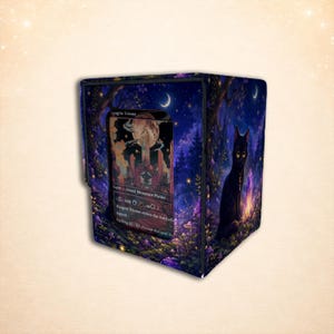 May include: A rectangular deck box featuring a dark fantasy forest scene with a black cat, glowing purple crystals, and a crescent moon. A clear window on the front displays a Raugrin Triome trading card with text including Land, Island, Mountain, Plains.