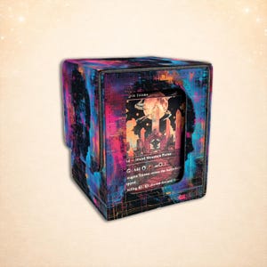 Peut inclure: Une boîte de rangement de cartes carrée avec un motif abstrait coloré en bleu, rose et violet. La boîte a une fermeture magnétique et une fenêtre révélant une carte avec une illustration de paysage fantastique. La carte indique "grin Triome".