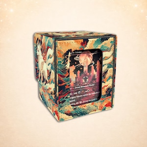 May include: A square deck box featuring a multi-colored illustration of a white fox with multiple tails and swirling clouds. The front panel has a rectangular cutout displaying a trading card with text reading Zagoth Triome and Island Mountain Plains.