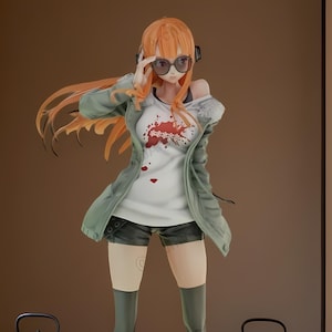 Può includere: Statuetta dettagliata di un personaggio con i capelli arancioni che indossa occhiali da sole, una maglietta bianca con un motivo floreale, una giacca verde e pantaloncini neri. La figura indossa stivali al ginocchio ed è in piedi su una base rotonda. Due teiere nere sono su una panca di legno.