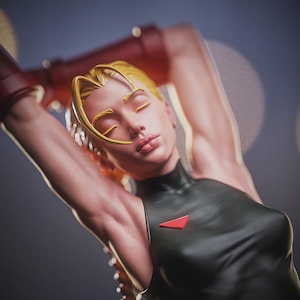 May include: A detailed figurine of a character with blonde hair in a braid, wearing a black bodysuit with a red triangle emblem. The figure has closed eyes and is posed with arms raised, wearing red armbands. The background is a blurred gradient of blue and gray.