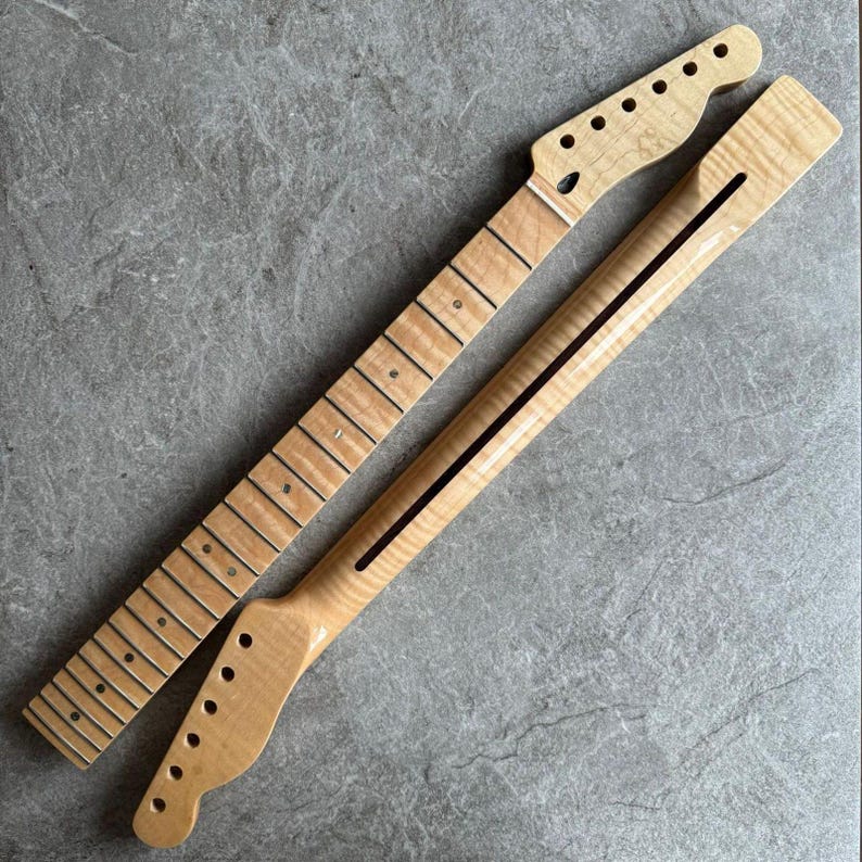 May include: Two unfinished maple guitar necks. One neck has frets and dot inlays, the other has a black stripe down the center. Both necks have a natural wood grain finish and are ready for assembly.