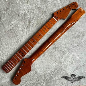 May include: Two guitar necks, one with frets and the other without, both made of a rich, reddish-brown wood. The necks are angled, showcasing the headstock with tuning peg holes. The wood grain is visible, and the finish is glossy.