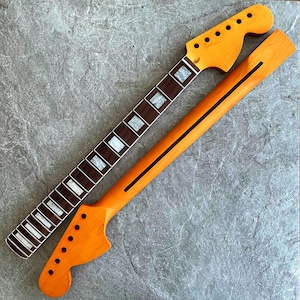 Könnte beinhalten: Zwei unfertige Gitarrenhälse. Der eine Hals ist hellorangefarben mit schwarzen Bundmarkierungen und einer Kopfplatte mit Stimmwirbellöchern. Der andere Hals ist dunkelbraun mit weißen Bundmarkierungen.