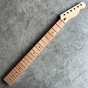 May include: A maple wood guitar neck with a natural finish. The neck features a headstock with pre-drilled holes for tuning pegs and a fretboard with inlaid fret markers. The wood grain is visible.