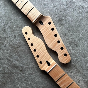 May include: Two unfinished guitar necks with a light wood grain pattern. Each neck has a headstock with tuning peg holes and a fretboard with black frets. The necks are angled, showcasing the wood's natural texture.