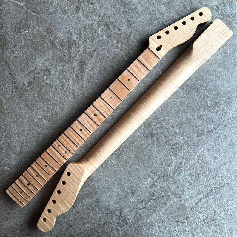 May include: Two unfinished maple guitar necks. One neck has frets and dot inlays, the other is a smooth, rounded neck. Both necks have a natural wood grain and are ready for assembly.
