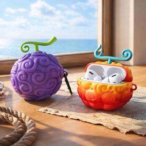 Può includere: Due custodie colorate per auricolari a forma di frutta stilizzata. Una è viola con uno stelo verde, l'altra è arancione e gialla con uno stelo blu e giallo. Le custodie sono su una superficie di legno con una corda nautica.