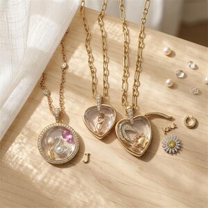 May include: Three gold-tone necklaces with clear locket pendants. One round locket contains a swan, tulip, and pink stone. Two heart-shaped lockets contain a ballet slipper, a crescent moon, and a paw print. Loose charms include a letter J, a daisy, and a horseshoe.