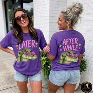 Puede incluir: Camisetas moradas con un cocodrilo de dibujos animados con gafas de sol en forma de corazón. La parte delantera de la camiseta dice "LATER" con acentos de estrella, y la parte trasera dice "AFTER WHILE". Las camisetas se combinan con pantalones cortos vaqueros.