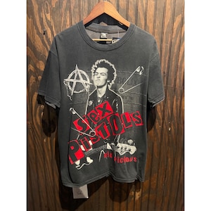 Könnte beinhalten: Ein schwarzes Kurzarm-T-Shirt mit einer Grafik von Sid Vicious. Das Design zeigt den Schriftzug "Sex Pistols" in fetten roten Buchstaben, ein Anarchie-Symbol, eine Sicherheitsnadel und den Namen "Sid Vicious" in kleiner roter Schrift.