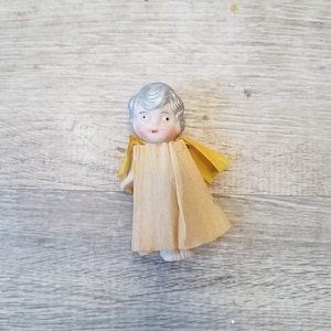 1900s silver haired bisque frozen Charlotte / penny doll with moving arms, crepe paper dress and cape