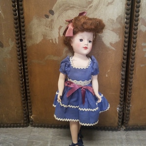 1950s doll with big red hair and bow, open and close eyes, a beautiful blue dress with vintage trim and blue tie shoes