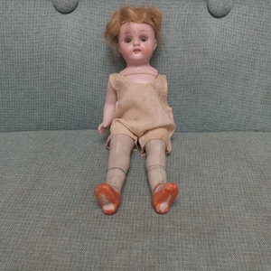 Antique 1900s Kestner ( mold 545) bisque little doll with jointed limbs, blue sleepy eyes, blonde wig and smiling lips showing teeth.