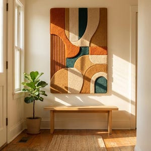 May include: A rectangular wall hanging featuring a tufted, textured surface with abstract geometric shapes in shades of burnt orange, deep teal, cream, and mustard yellow, arranged in a layered composition with varying pile heights and patterns.