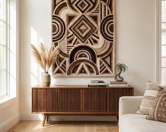 May include: A rectangular wall hanging featuring a tufted geometric pattern in shades of cream, tan, and dark brown. The design consists of concentric circles, squares, and linear elements, creating a textured, layered appearance on the wall.