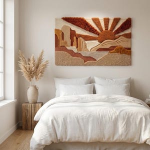May include: A rectangular tufted wall hanging featuring a desert landscape with a rising sun. The design incorporates textured layers in shades of rust, terracotta, beige, and cream, depicting stylised rock formations and sun rays.