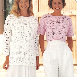 Può includere: Due donne indossano top all'uncinetto fatti a mano. Uno è un top bianco a maniche lunghe, l'altro un crop top rosa a maniche corte. Entrambi i top presentano un motivo floreale traforato. Sono abbinati a pantaloni bianchi.