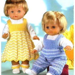 May include: Two dolls wearing knitted outfits. One doll is dressed in a yellow and white chevron patterned dress with matching socks. The other doll is wearing blue overalls with white stripes and matching socks. Both dolls have blonde hair and are wearing white long-sleeved shirts.