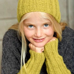 May include: A young person with blonde hair and blue eyes wearing a mustard yellow knit hat and matching fingerless gloves. The person is wearing a gray sweater. The hat and gloves are ribbed.