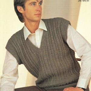 Könnte beinhalten: Eine gerippte, olivgrüne Strickweste mit V-Ausschnitt, getragen über einem weißen Hemd mit Kragen. Das Bild enthält die Maße 86-112 cm und 34-44 Zoll. Die Weste ist ein klassischer Stil, geeignet zum Überziehen.