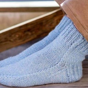 May include: A pair of light blue knitted socks. The socks are made of a soft, textured yarn and feature a ribbed cuff and a textured pattern on the foot. The socks are designed for comfort and warmth.