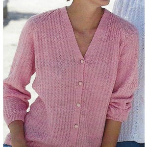 May include: A light pink cardigan with a V-neck and long sleeves. The cardigan has a button-up front with five buttons. The knitwear has a textured pattern.