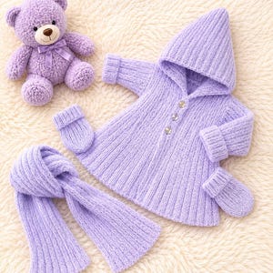 May include: A lavender knitted set consisting of a hooded coat with three buttons, a pair of mittens, and a scarf, accompanied by a matching lavender teddy bear with a satin ribbon bow around its neck. The items feature a ribbed texture throughout.
