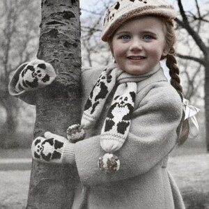 Może przedstawiać: Młoda dziewczyna w jasnoszarym płaszczu, czapce, szaliku i rękawicach. Czapka, szalik i rękawice mają czarno-biały wzór pandy. Dziewczyna uśmiecha się, stojąc obok drzewa. Obraz ma klimat vintage.