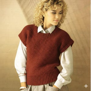 May include: A claret-coloured knitted vest with a ribbed hem and short sleeves. The vest is worn over a white collared shirt. The style is classic and preppy.