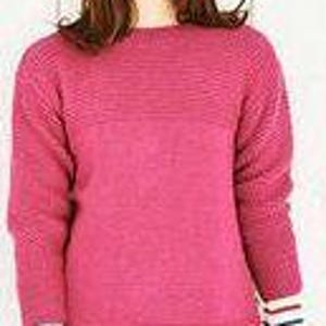 May include: A magenta-colored sweater with a ribbed design across the chest and long sleeves. The cuffs feature a white band with blue and red stripes. The sweater is a crew neck style.