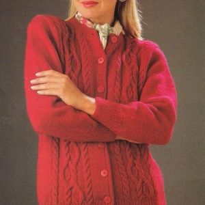 May include: A red cable-knit cardigan sweater with a button-up front. The sweater has a classic design with textured cable patterns and ribbed cuffs. The woman is wearing a floral print scarf under the sweater.