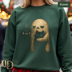May include: Forest green sweatshirt featuring a graphic of a ghost-like figure holding a black cat. The ghost is holding a steaming mug with the word "MEH" printed below. The design is in shades of gold and black.