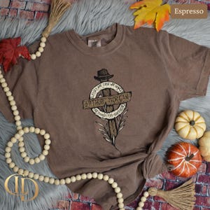 May include: Espresso-coloured t-shirt with a graphic of a cross, a hat, and the text "ARTHUR MORGAN". The design includes the phrases "Blessed are those who hunger" and "and thirst for righteousness".