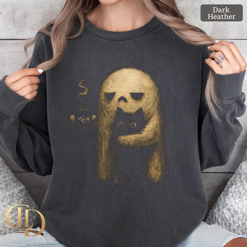 May include: Dark heather gray sweatshirt featuring a gold-colored ghost-like figure embracing a black cat. The ghost holds a cup of coffee with the word "MEH" printed on it. A unique design for cat lovers and those who enjoy spooky themes.