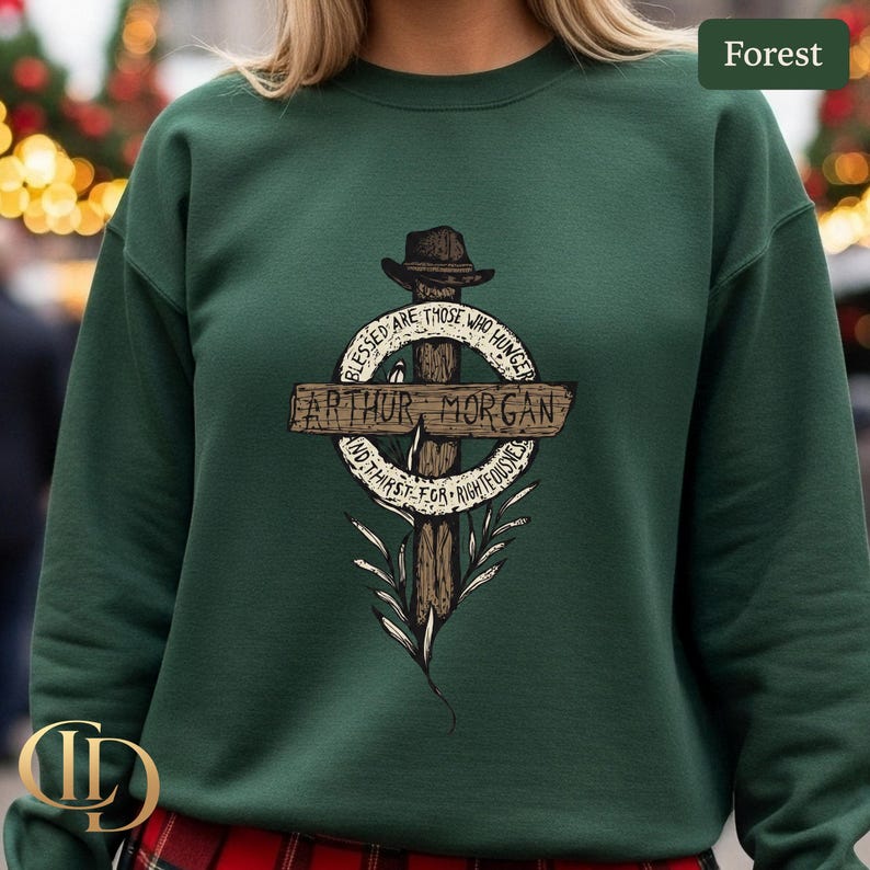 May include: A forest green sweatshirt with a graphic design. The design features a cross, a hat, and the text "ARTHUR MORGAN". The design also includes the phrases "BLESSED ARE THOSE WHO HUNGER" and "AND THIRST FOR RIGHTEOUSNESS".