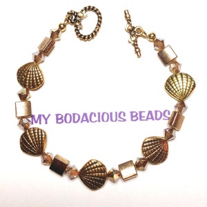 May include: Gold tone bracelet with a seashell charm and crystal beads.  The bracelet has a toggle clasp.
