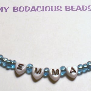 May include: A blue and white beaded bracelet with the name "EMMA" spelled out in white heart-shaped beads.