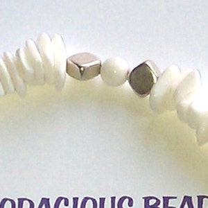 May include: White shell beads with silver square beads and a white bead in between.