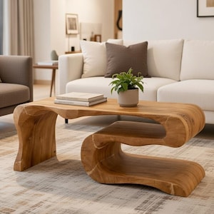 May include: A unique, wooden coffee table with a natural, organic design. The table features a flowing, sculptural shape with a light brown finish. A small potted plant and books rest on the table, which is placed in a modern living room.