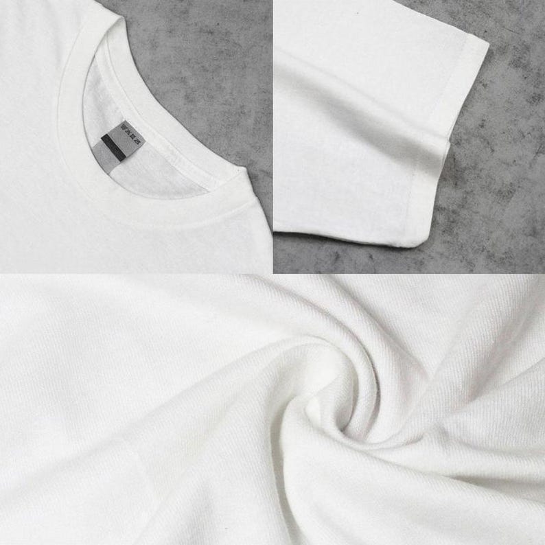 May include: A plain white t-shirt featuring a crew neckline and short sleeves. The garment is made of a solid white fabric with a visible texture. A small, rectangular grey tag is attached to the inside of the collar at the back neckline.