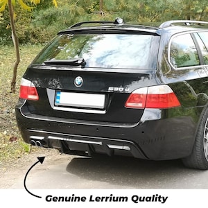 Może przedstawiać: Czarny samochód kombi BMW 530d widziany od tyłu, wyposażony w ciemny tylny dyfuzor z dwiema rurami wydechowymi po lewej stronie, wycieraczkę tylnej szyby i emblemat BMW. Tekst Genuine Lerrium Quality znajduje się pod pojazdem.