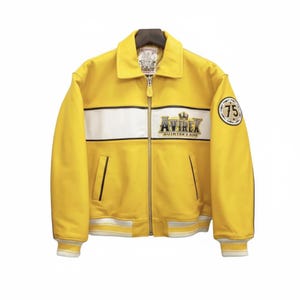 May include: Yellow leather jacket with a white stripe across the chest and the text "AVIREX". Features a zip closure, two front pockets, and a patch with the number "75". The jacket has a ribbed hem and cuffs.