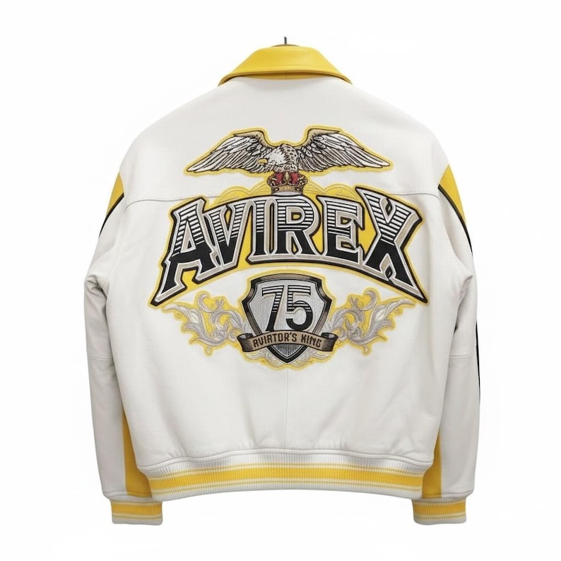 May include: White leather jacket with yellow accents and the "AVIREX" logo on the back. The jacket features a yellow collar, cuffs, and side stripes. The back also displays an eagle emblem and the text "75 AVIATOR'S KING".