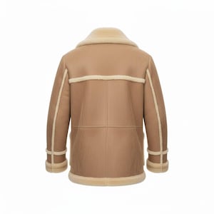 May include: A tan shearling coat with a cream-colored shearling collar and trim. The coat features a classic design with a double-breasted closure and a warm, inviting aesthetic. The back view showcases the coat's tailored fit and quality construction.