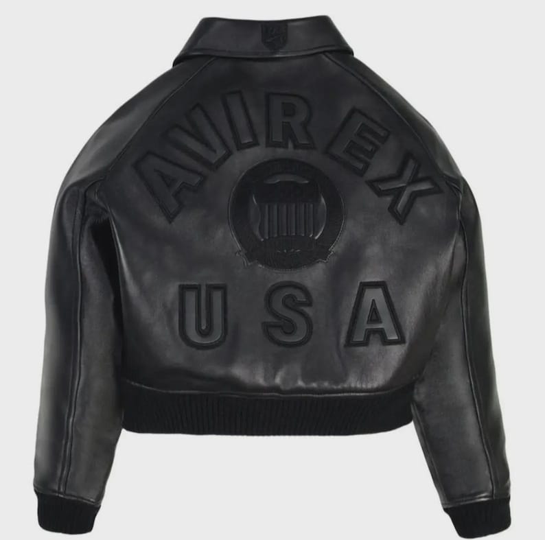 May include: Black leather jacket featuring the word "AVIREX" arched across the back, above "USA". The jacket has a ribbed hem and cuffs. A circular emblem is centered between the brand name and the country.