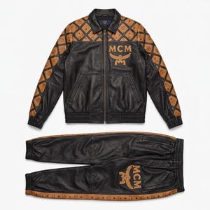 May include: A black leather jacket and matching joggers set. The jacket features a tan diamond-patterned yoke and sleeves with the MCM logo, and a large MCM logo on the chest. The joggers have tan side panels with the MCM logo and a large MCM logo on the leg.