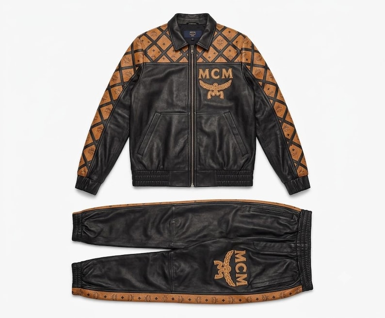 May include: A black leather jacket and matching joggers set. The jacket features a tan diamond-patterned yoke and sleeves with the MCM logo, and a large MCM logo on the chest. The joggers have tan side panels with the MCM logo and a large MCM logo on the leg.