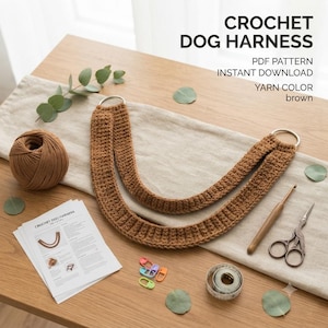 Könnte beinhalten: Ein braunes Häkelgeschirr für Hunde mit zwei silbernen Metallringen, einem Knäuel braunem Garn, einer Häkelnadel aus Holz, einer Metallschere, bunten Maschenmarkierern aus Kunststoff, einem Maßband und einer gedruckten Anleitung.