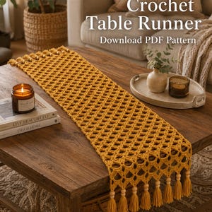Może przedstawiać: Musztardowy szydełkowy bieżnik na stół z rombowym wzorem i frędzlami. Wyświetlany jest tekst "Crochet Table Runner" i "Download PDF Pattern". Świeca i książki leżą na drewnianym stole.